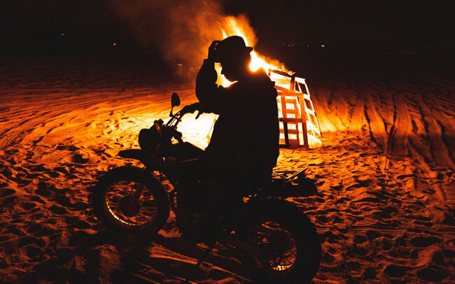 焚火の前でバイクにまたがる人